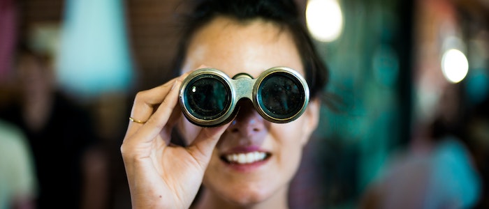 Woman holding binoculars looking into distance